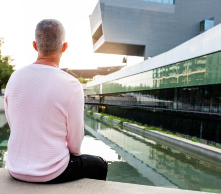 Caucasian man with pink sweater looking to a serene modern city view. Relaxing in the city. Copy space. Lifestyle concept.